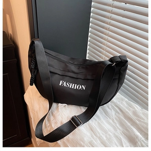 Detail showing fashion logo on black waterproof crescent bag with adjustable strap