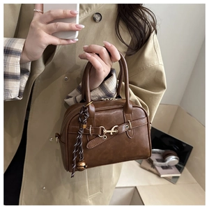 Close-up of vintage brown tote bag with gold horsebit buckle and woven bell charm