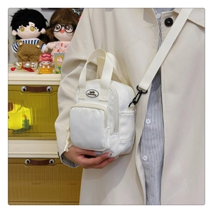 Detailed view of white mini nylon crossbody bag featuring multiple zipper pockets and logo