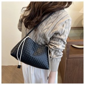 Close-up detail of black woven leather shoulder bag with stylish white drawstring