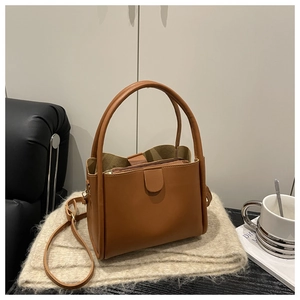 Detail of caramel leather bucket bag featuring interior pouch on knit fabric background