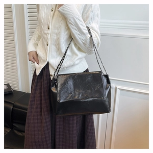 Sac bandoulière classique en cuir plissé noir avec chaîne argentée porté par un mannequin