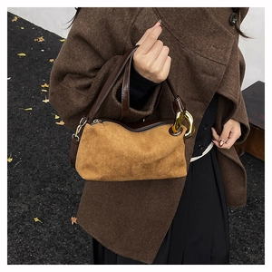 Brown suede shoulder bag with leather strap and gold ring detail shown on a model