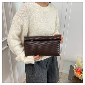 Détail de la pochette en cuir marron foncé tressé à la main, texture de luxe et motif