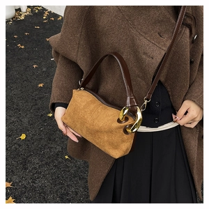 Detail view of retro suede handbag with gold ring hardware and adjustable strap