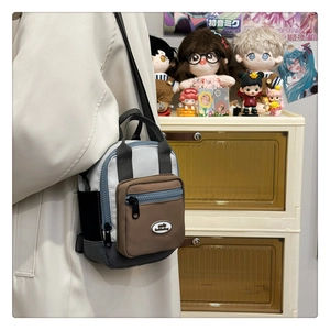 Detail of color-blocked mini crossbody bag showing zippered pockets and nylon strap