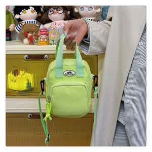 Detail of neon green nylon mini bag with adjustable strap and front zipper pocket