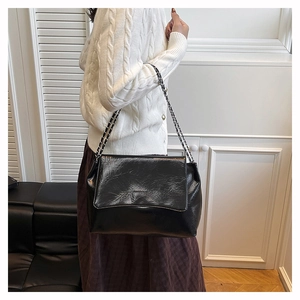 Détail du sac à bandoulière noir en similicuir plissé avec une bandoulière en chaîne