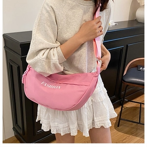 Pink crescent crossbody bag with white FASHION logo and adjustable strap in use