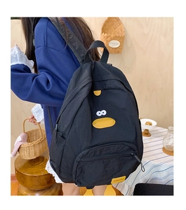 Detail of black cartoon duck backpack featuring yellow beak and 3D feet on nylon fabric