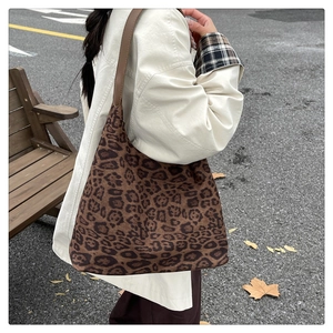 Sac fourre-tout léopard avec lanières en cuir marron porté à l'épaule en décor d'automne