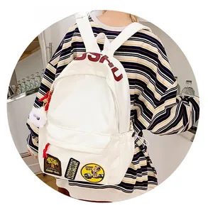 Close-up of white canvas backpack featuring red KUSHU embroidery and patches