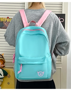 Detail of mint green nylon backpack with pink zippers on a model back for high school