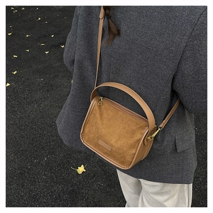 Brown matte vintage crossbody bag with suede texture shown in an autumn outdoor setting