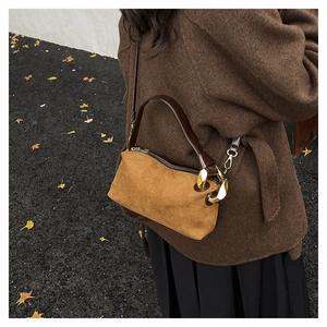 Detail of vintage brown suede pillow bag with gold metal rings and leather strap
