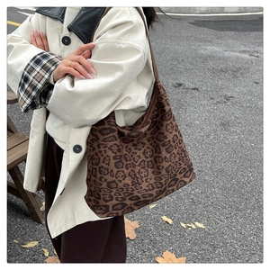 Gros plan d'un grand sac à bandoulière léopard porté à l'épaule en extérieur