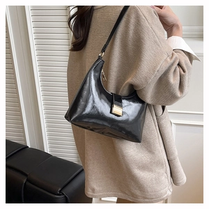 Detail of black glossy hobo bag with golden hardware shown as a stylish shoulder bag