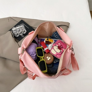 Pink large capacity travel bag with top handles and shoulder strap shown with essentials