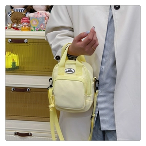 Close-up of yellow canvas mini crossbody bag featuring dual handles and a smile woven label