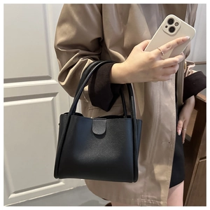 Detail of structured black tote bag with grain leather texture and metallic clasp