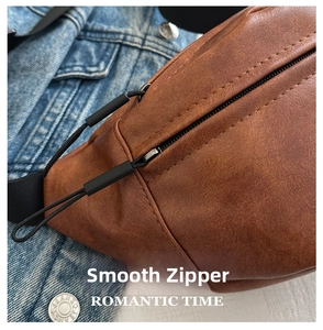 Detailed view of the brown leather texture and smooth black zipper on a crossbody bag