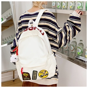 Close-up of white canvas backpack featuring red KUSHU lettering and vintage patches