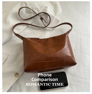 Brown faux leather tote bag detail with smartphone for size comparison on a white blazer