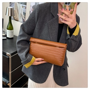 Pochette en cuir tressé marron montrée dans un selfie miroir pour un look décontracté chic