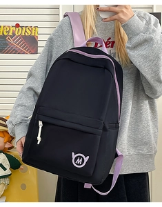 Detail of black nylon backpack with purple straps and contrast stitching and M logo