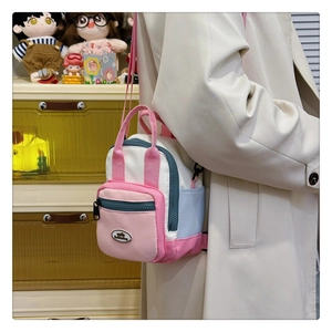 Detailed view of mini canvas crossbody bag in pink white and blue with adjustable straps