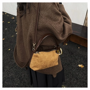 Détail du sac polochon en daim kaki avec poignées en cuir marron et anneaux dorés