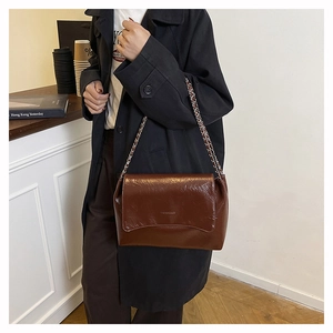 Détail du sac à bandoulière en cuir ciré marron foncé avec chaîne argentée et logo
