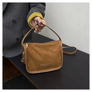 Detail of vintage brown suede handbag featuring matte texture and gold metal hardware