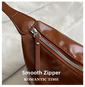 Detail of smooth silver zipper and soft brown leather texture on a large tote bag