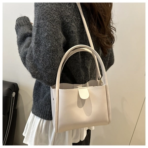 Rear view of white minimalist square crossbody bag worn by model in a stylish interior