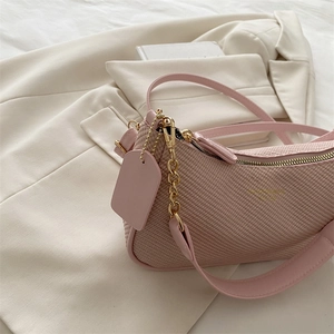 Pink minimalist shoulder bag with textured fabric and gold chain on beige blazer