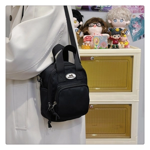 Detail of black nylon crossbody bag with smile fashionbag logo and woven zipper pull
