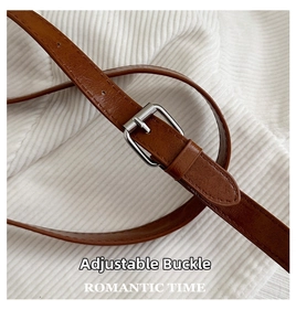 Detailed close-up of brown leather shoulder strap with silver adjustable metal buckle