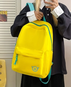 Macro detail of vibrant yellow backpack with sky blue accents and circular M logo