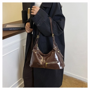 Sac hobo en cuir verni marron avec détails dorés présenté dans un cadre de vie moderne
