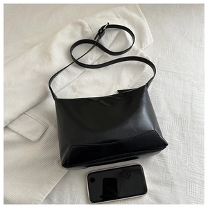 Detail of black glossy vintage leather tote bag with smartphone for size reference
