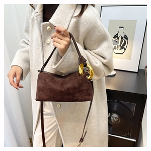 Détail du sac Boston en daim marron avec un grand anneau doré décoratif sur le côté