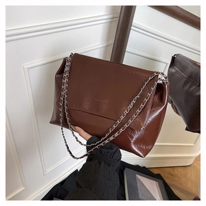 Détail d'un sac cabas marron à chaîne en cuir plissé brillant avec logo embossé