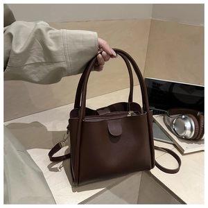 Detail view of large dark brown leather tote bag with handles and detachable shoulder strap