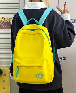 Rear view of model wearing a bright yellow and blue contrast color nylon backpack
