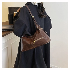 Detailansicht der dunkelbraunen Hobo-Tasche aus glänzendem Leder mit goldener Reißverschluss