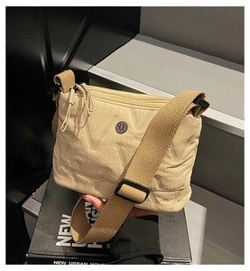 Détail du sac bandoulière en nylon matelassé beige avec large sangle et logo en métal