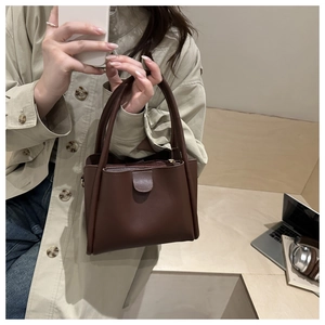 Detail of dark brown leather tote bag with sturdy handles and smooth top zipper closure