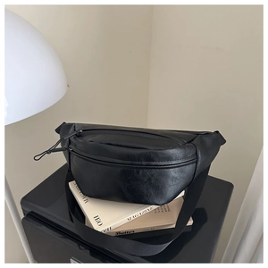 Detail of a black leather chest bag featuring dual zippers and adjustable woven strap