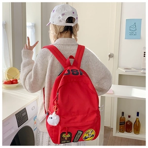 Detailed view of red canvas backpack featuring vintage patches and USA lettering